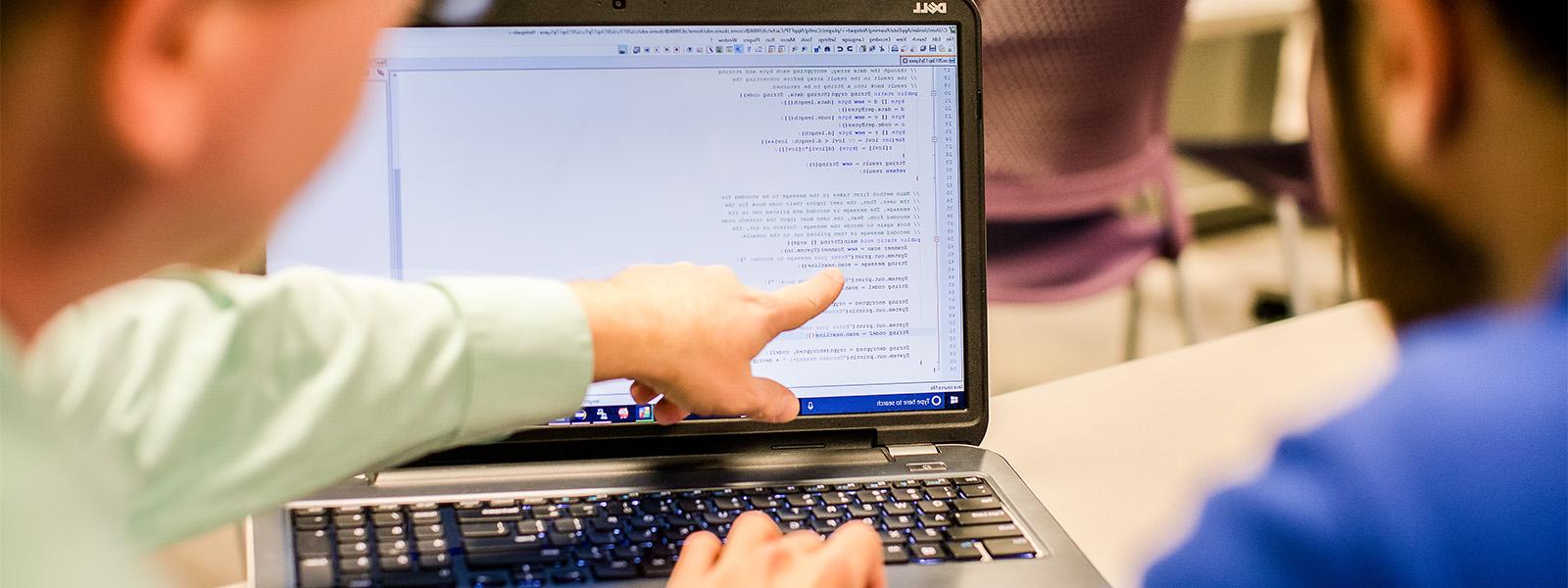 student looks at computer screen while giving class presentation